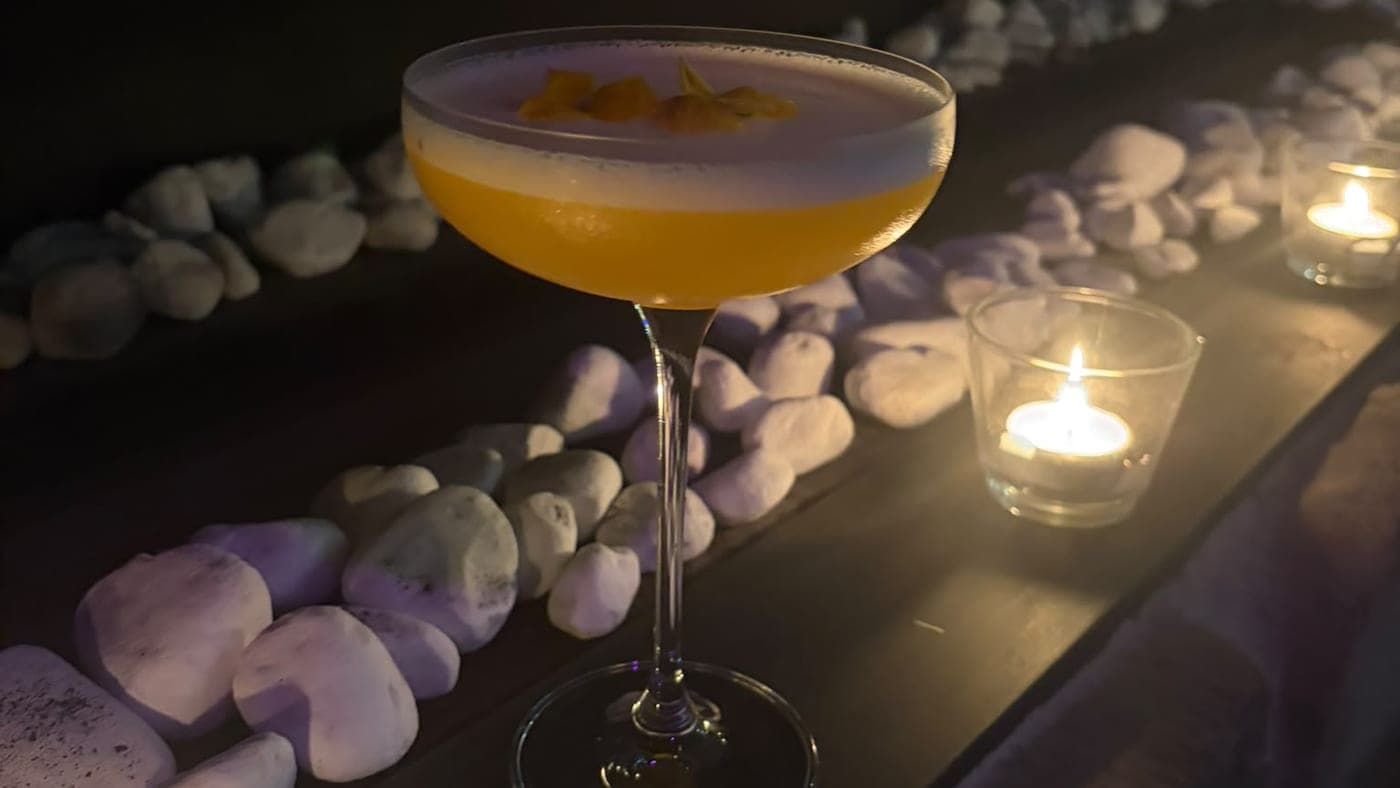 Cocktail servi à la lueur des bougies dans l'ambiance tamisée d'Aura Spa, spa privatif près de Bruxelles pour une soirée entre amis ou un enterrement de vie de jeune fille